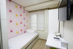 花柄の壁の部屋に白いベッドが置いてある。