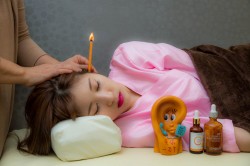 耳に火がついた棒を刺した女性。